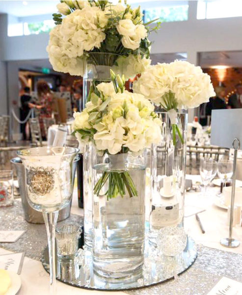 Wedding centrepice of three different height cyliner vases, each with hand-tied bouquet of cream flowers
