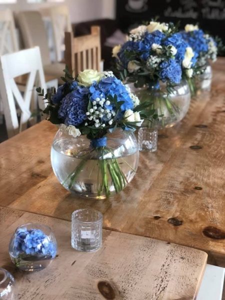Deep blue flowers arranged as hand-toed bouquets placed in fish bowl vases
