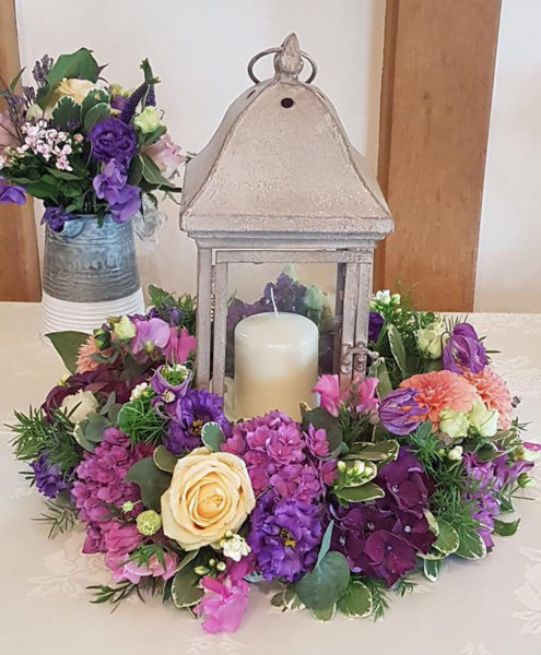 Rustic lantern centrepice surrounded by a ring of purple flowers