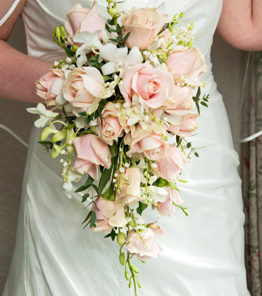 Bride holding a bouquet with white orchids with pale pink roses and lily of the valley